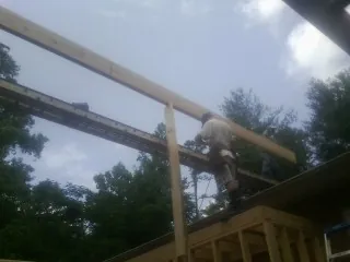 Carpenter setting a ridge beam over a new addition frame — Ice Dam Removal by Roofing Brothers in Cushing