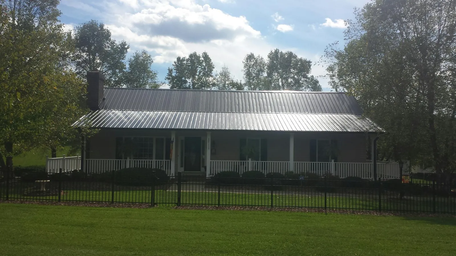 Gray metal roof on a brick ranch with a full width front porch — Gutter Guard Installation work by our crew in Cushing