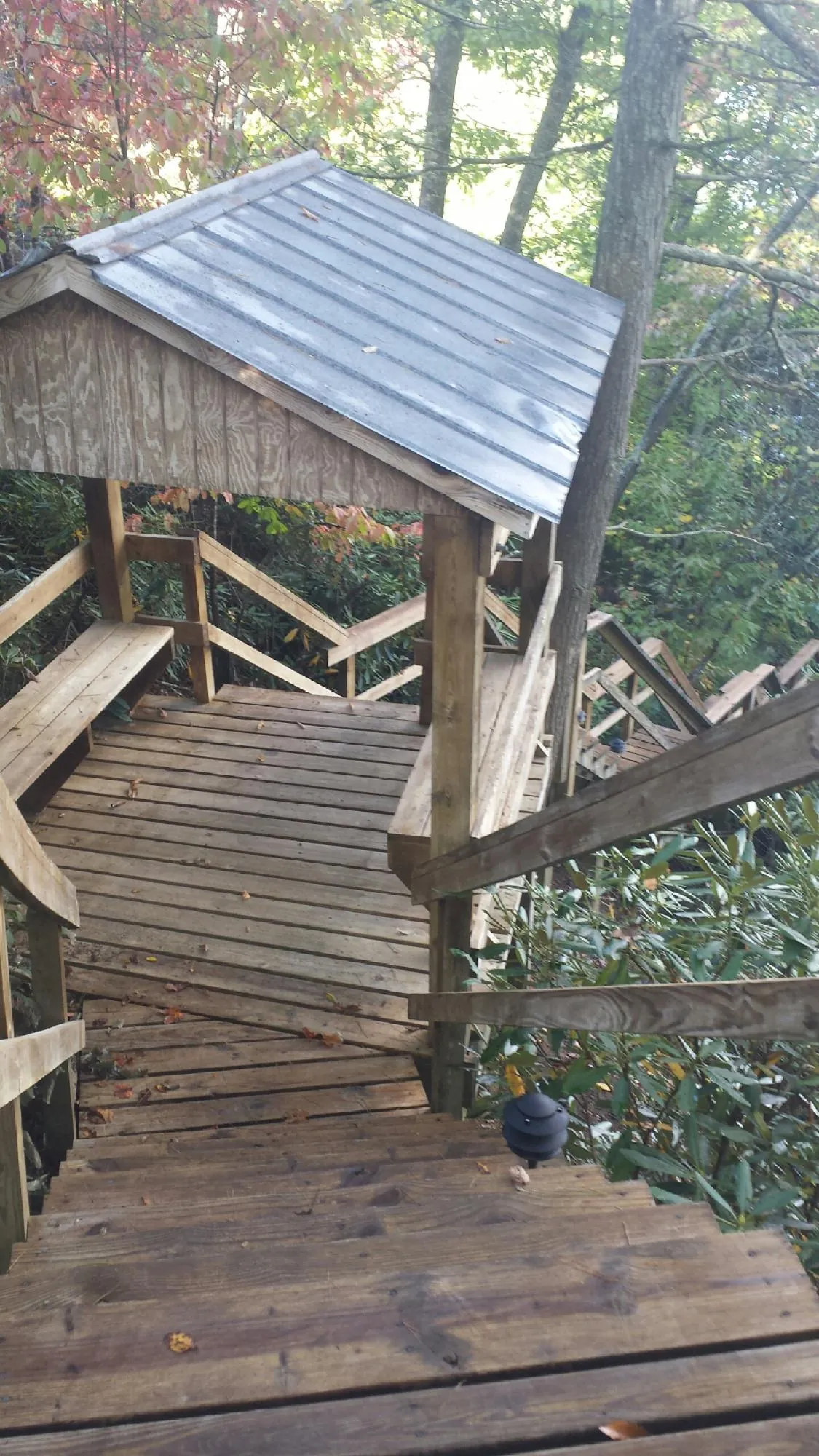 Metal roofed shelter over wooden steps on a wooded walkway — Skylight Repair & Installation work by our crew in Cushing