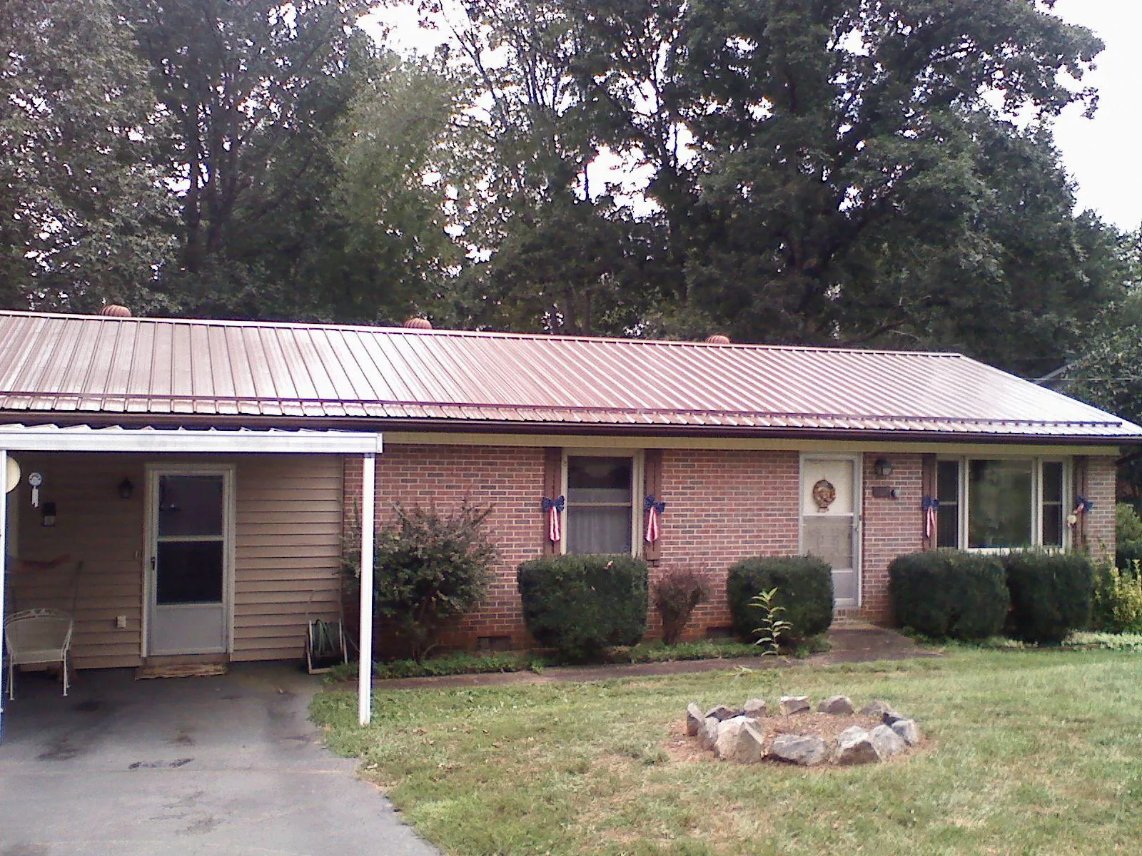 Bronze metal roof and carport on a brick ranch home — Roof Repair work by our crew in Cushing